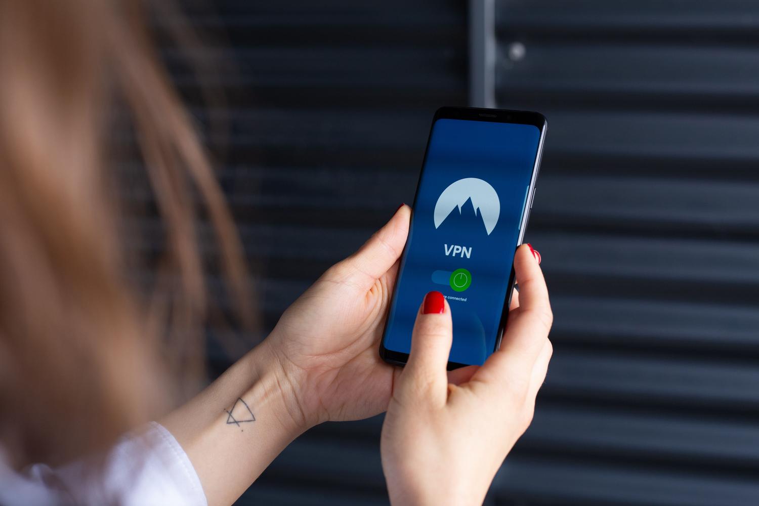 Primer plano de una persona activando una aplicación de VPN en su teléfono móvil para cambiar su ubicación virtual.